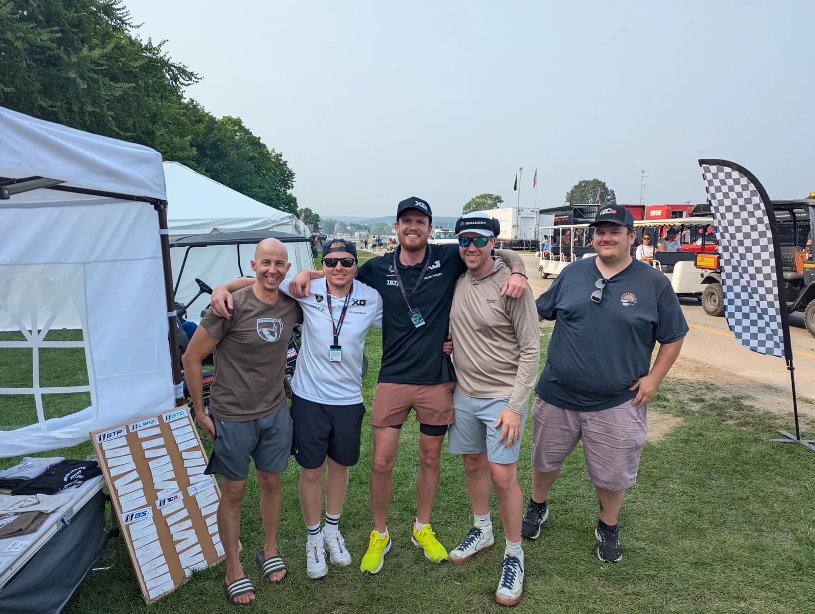 Five people gathered beside a Skid Mark outdoor simulator setup in Wisconsin