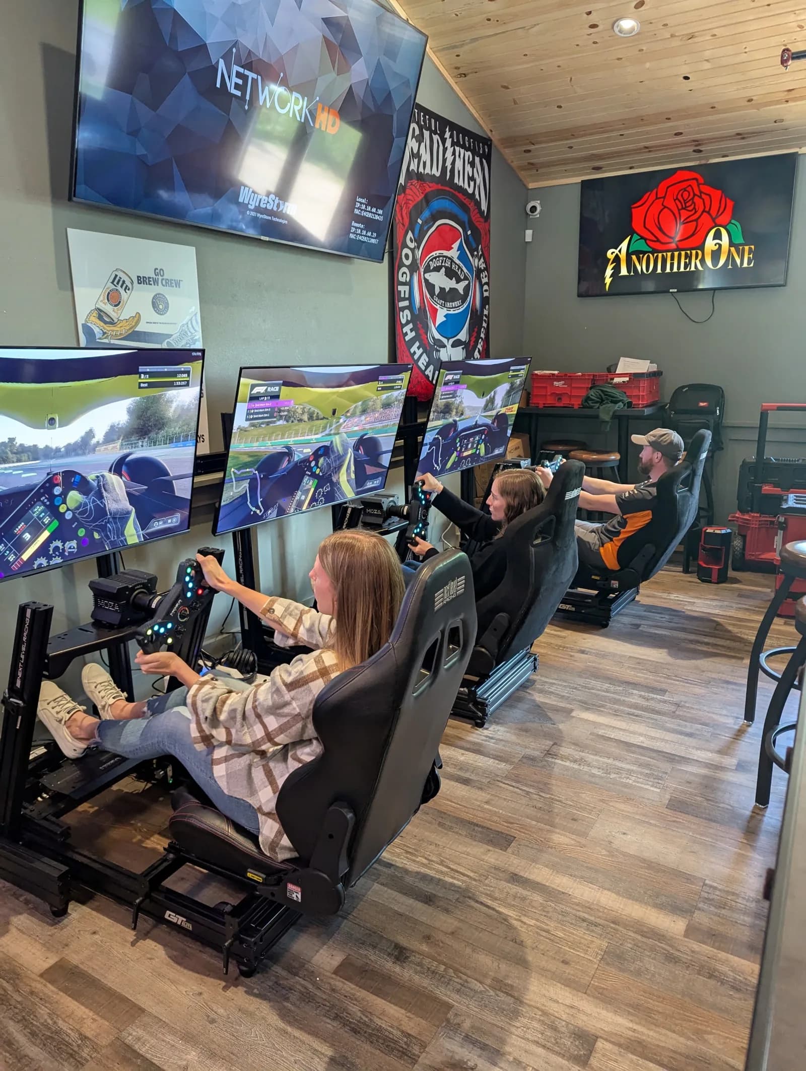 Three guests racing side by side on Skid Mark simulators inside a Wisconsin brewery