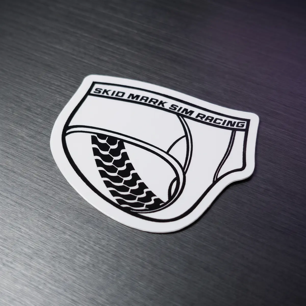 Skid Mark Sim Racing 2.5-inch logo sticker on a graphite surface