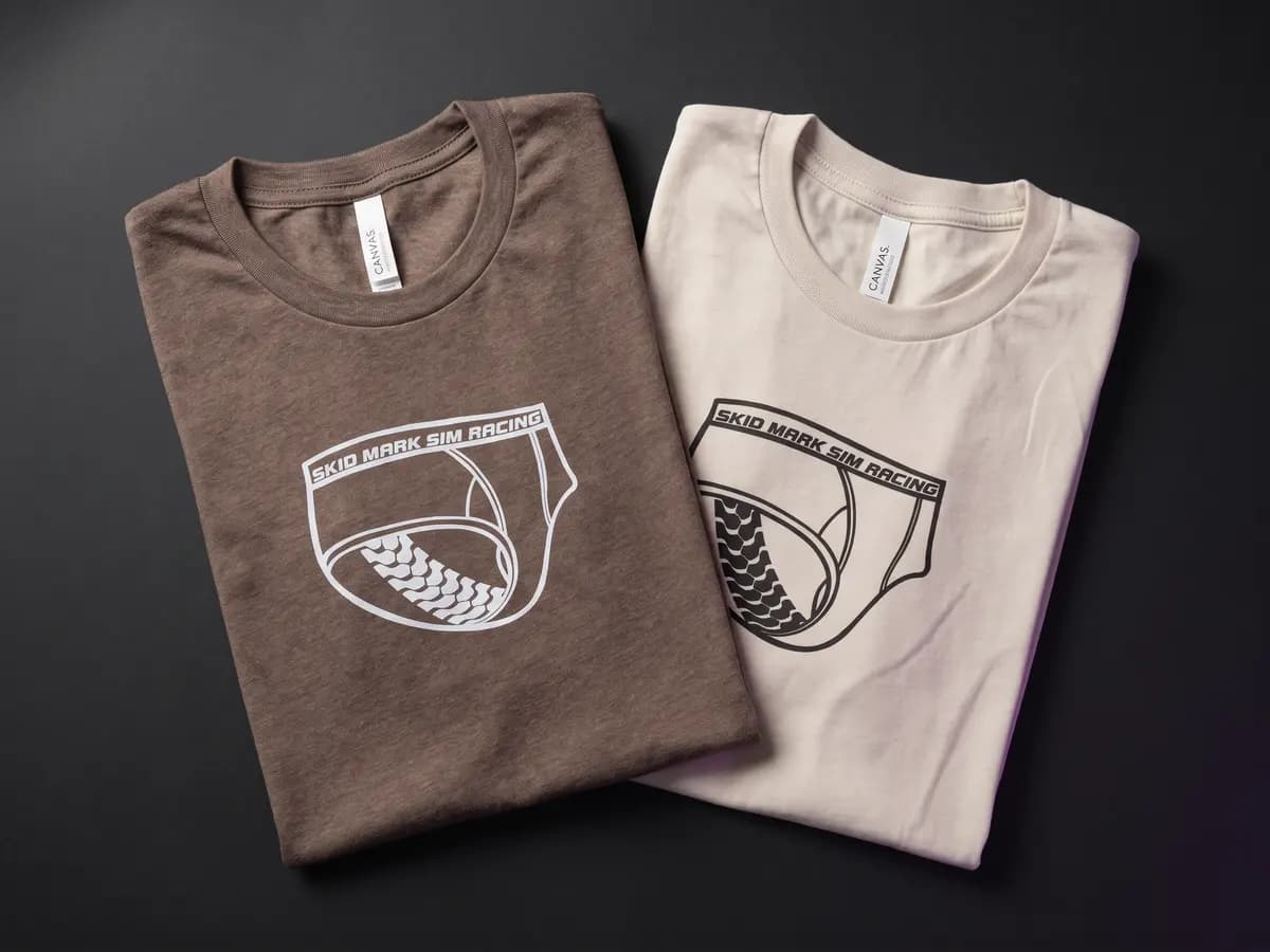 Brown and light Skid Mark Sim Racing logo shirts arranged together on a graphite surface